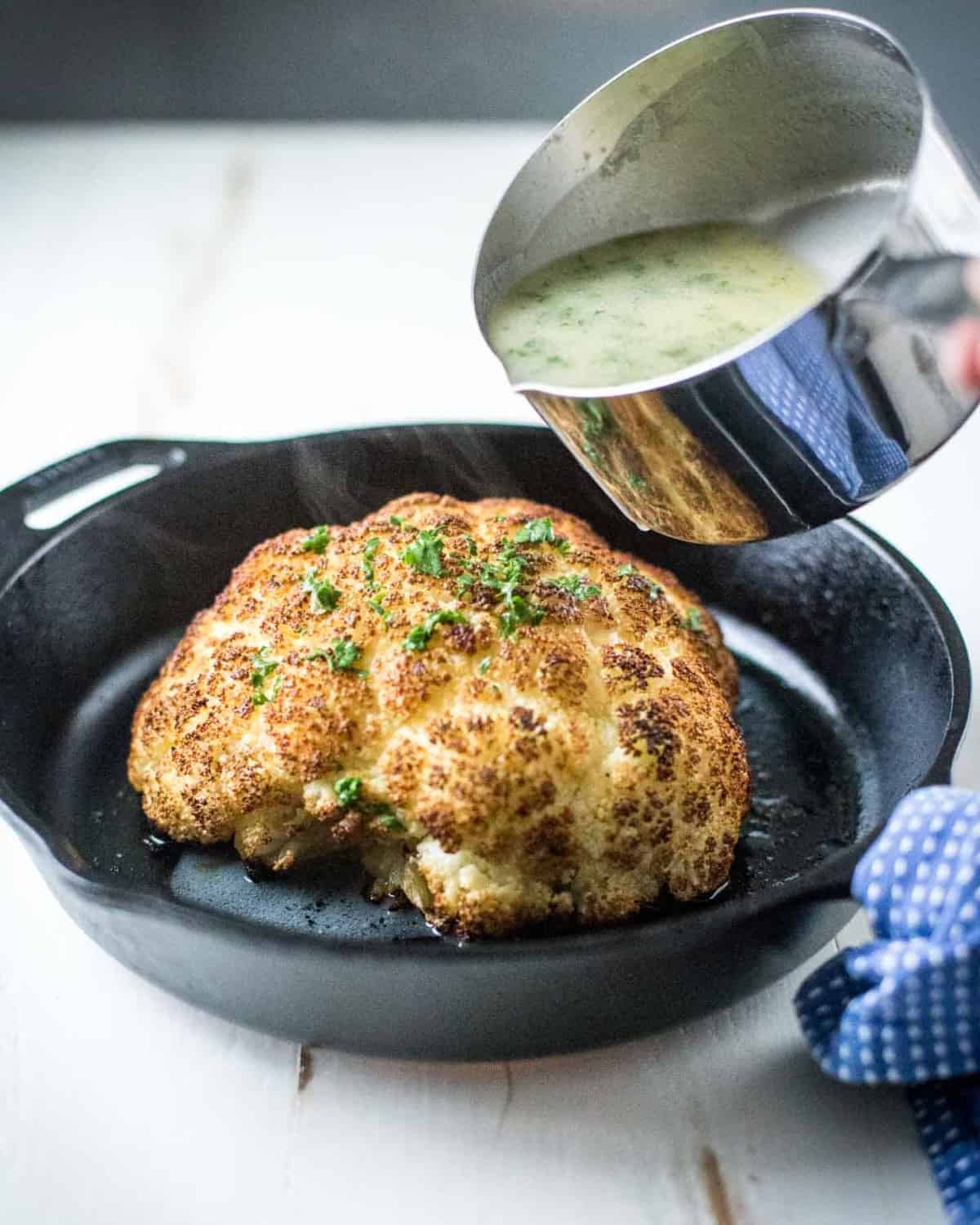 pouring butter sauce over Whole Roasted Cauliflower