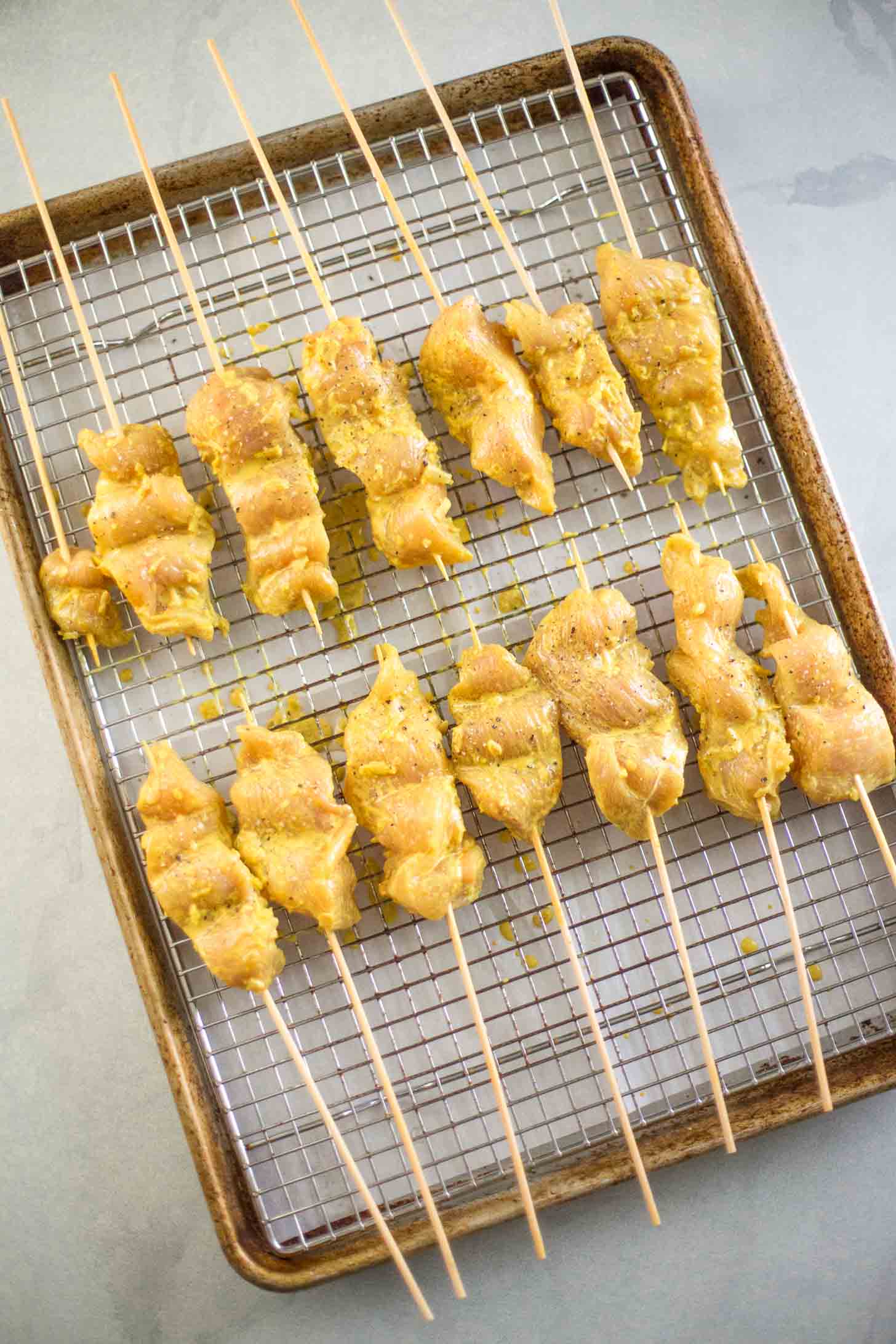 chicken satay on skewers on a sheet pan