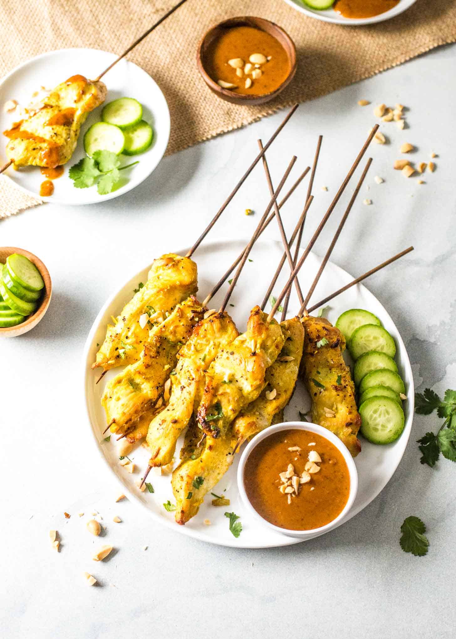 overhead image of chicken satay skewers on a white plate