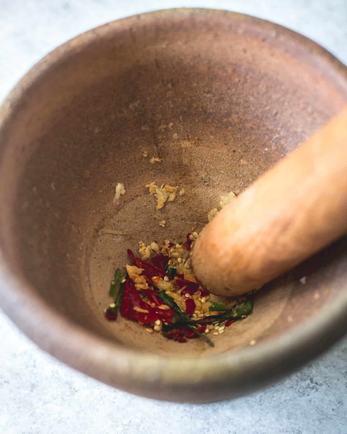 grinding Thai spices in mortar and pestle