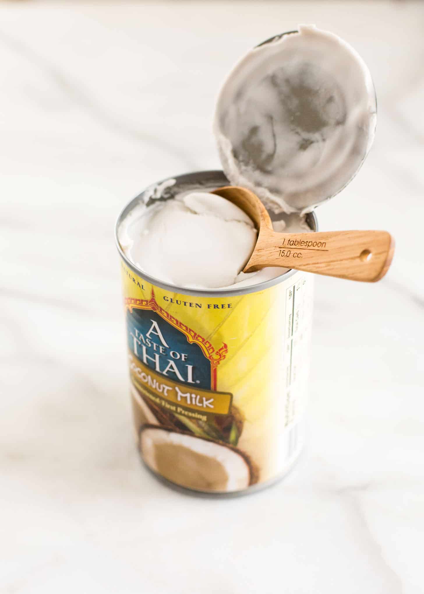 a wooden spoon in a can of coconut milk