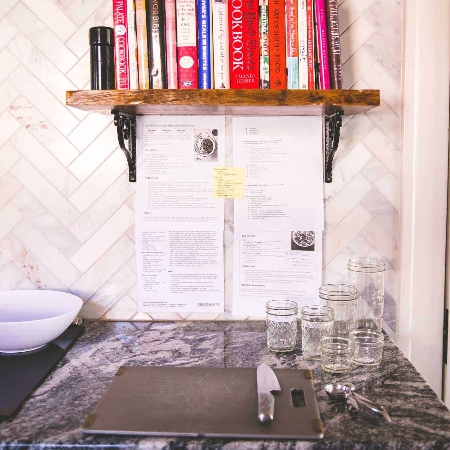 a cutting board, knife and glass jars on a grey countertop