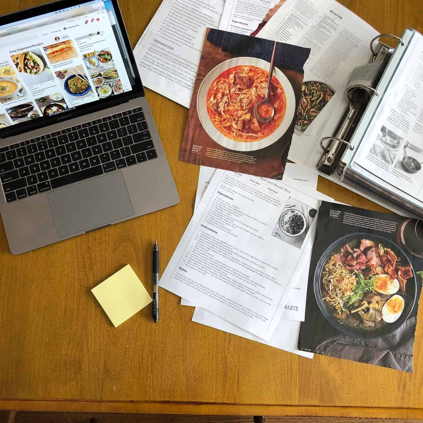 a computer and recipes on a wood table