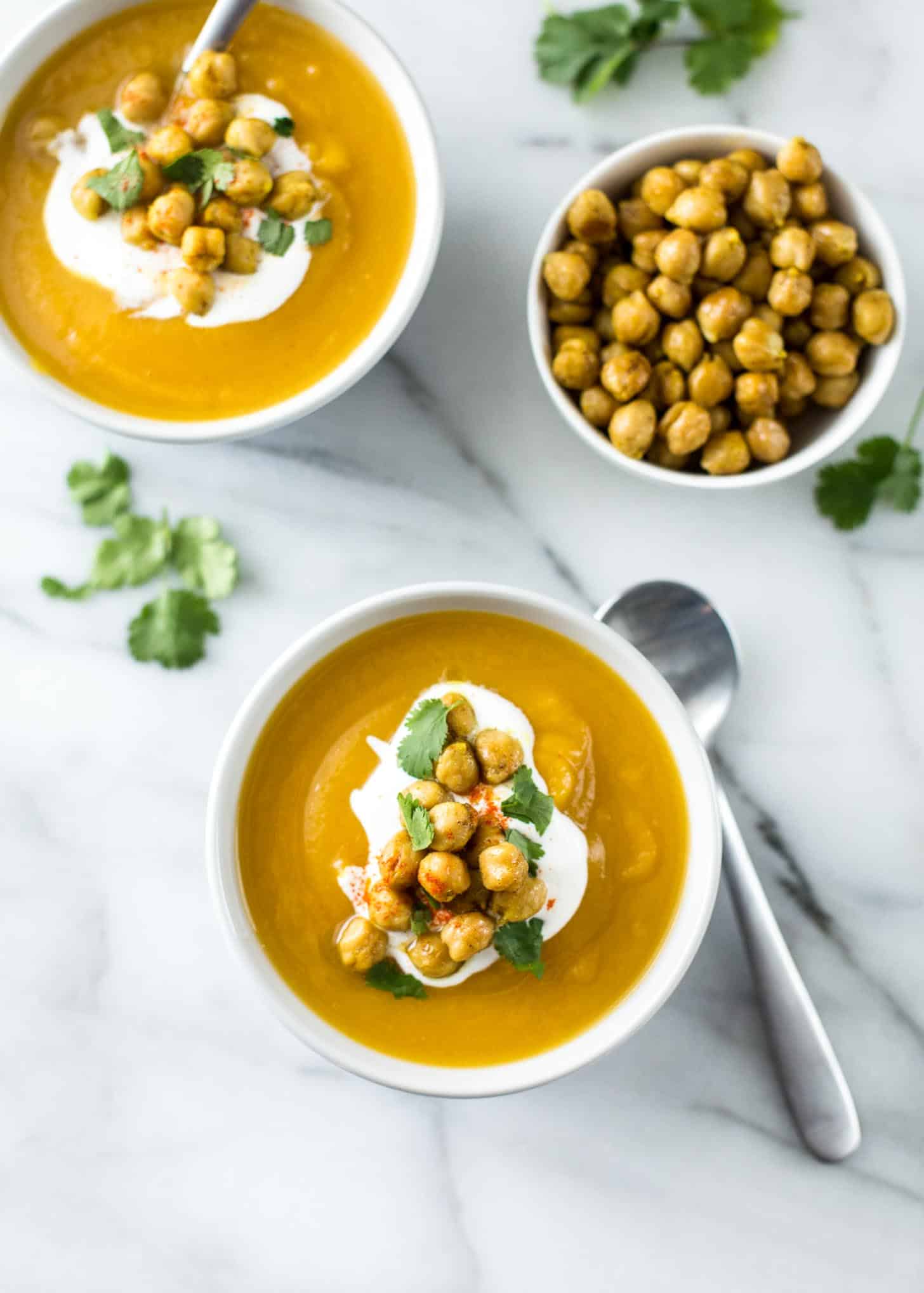 2 bowls of Soup topped with sour cream on a white countertop