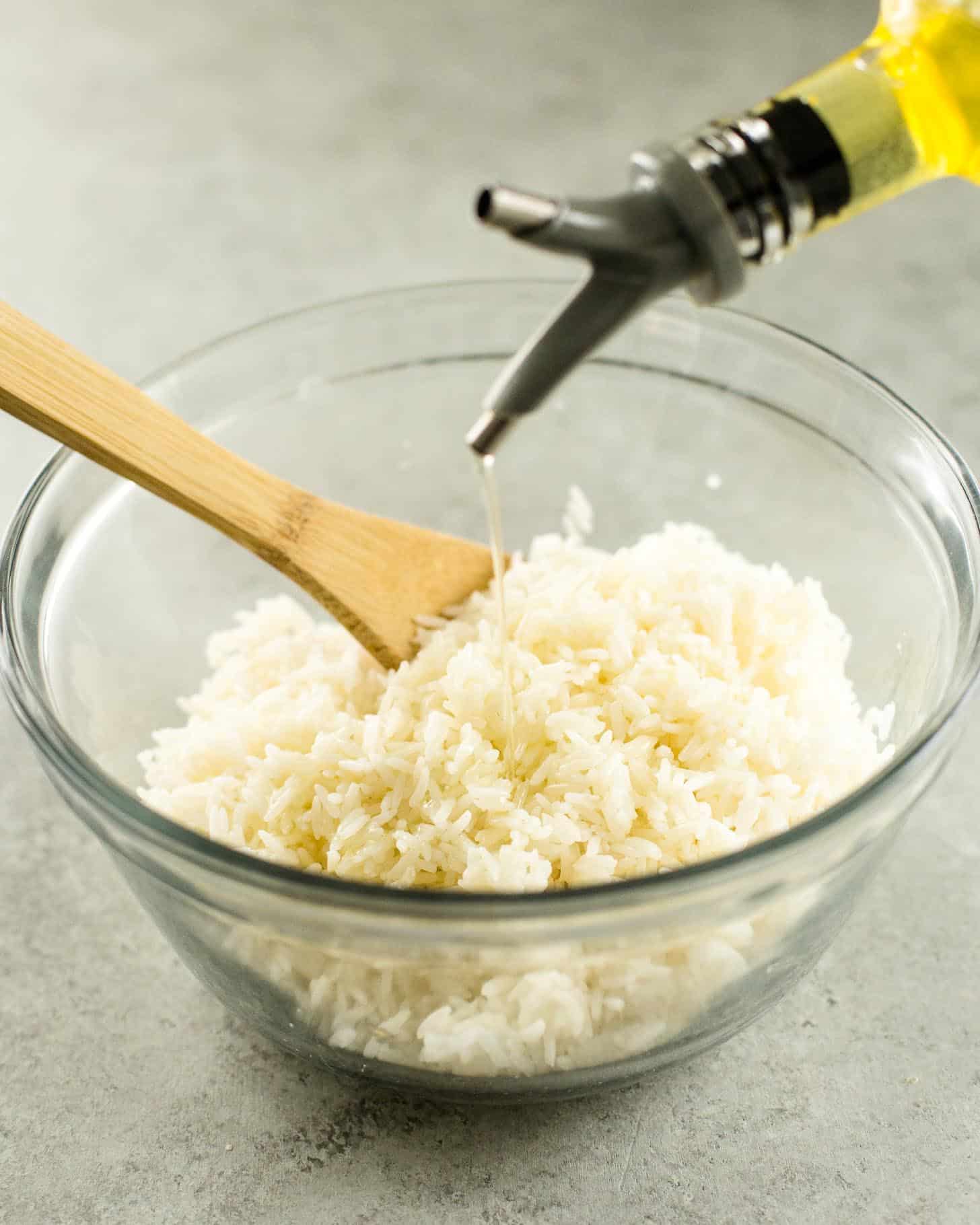 pouring oil on rice in a clear glass bowl