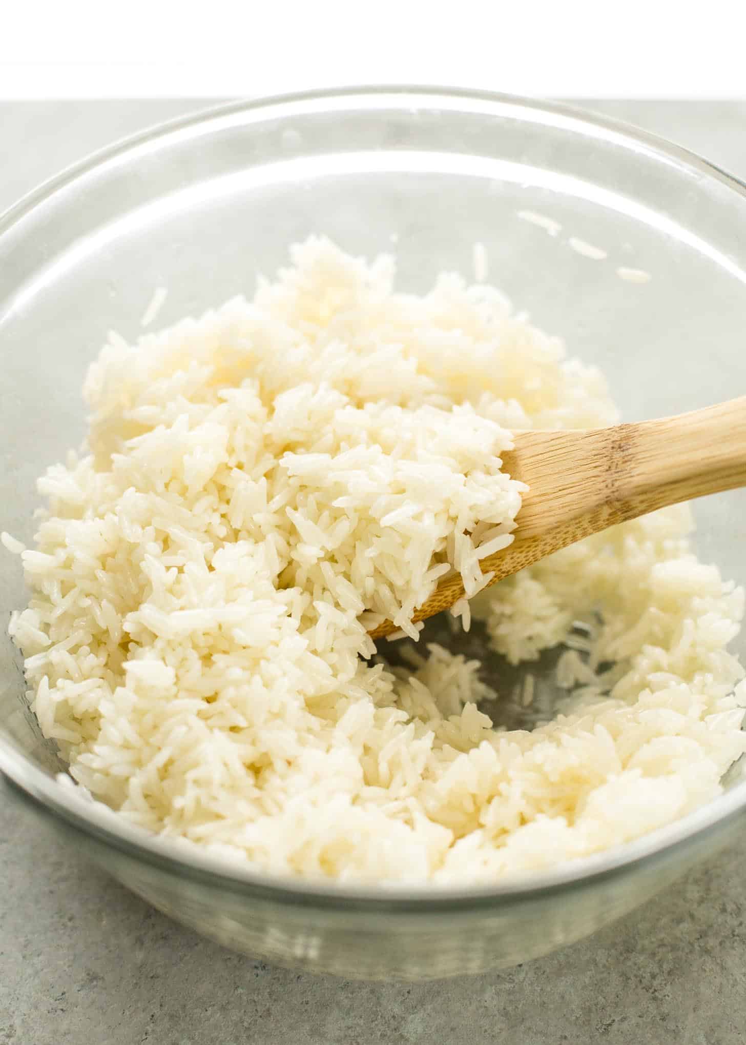 cooked Rice and a wooden spoon in a clear glass bowl