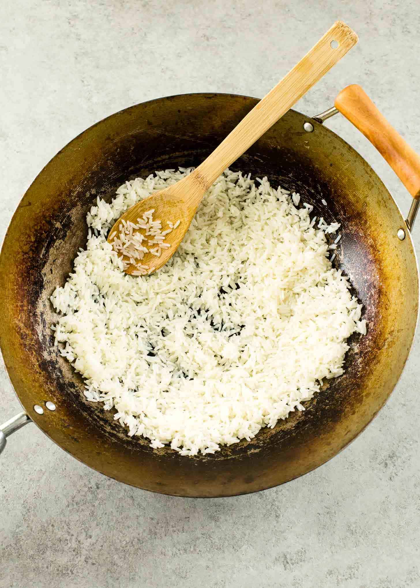 stirring Rice in a wok with a wooden spoon