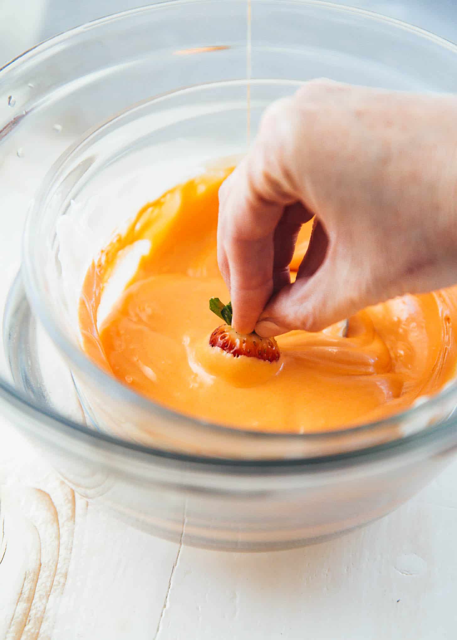 dipping strawberries in orange colored white chocolate