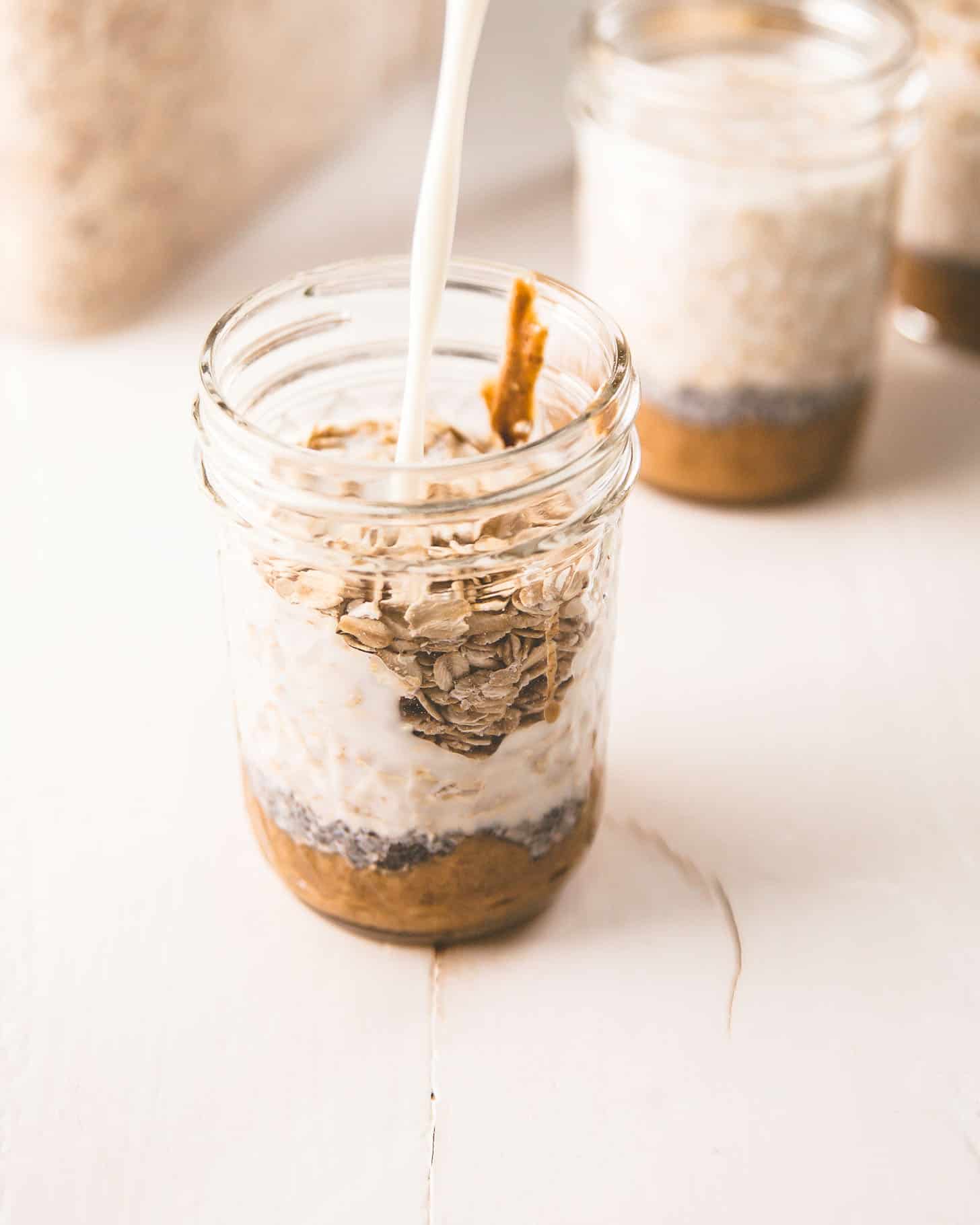 adding milk to overnight oats in a mason jar