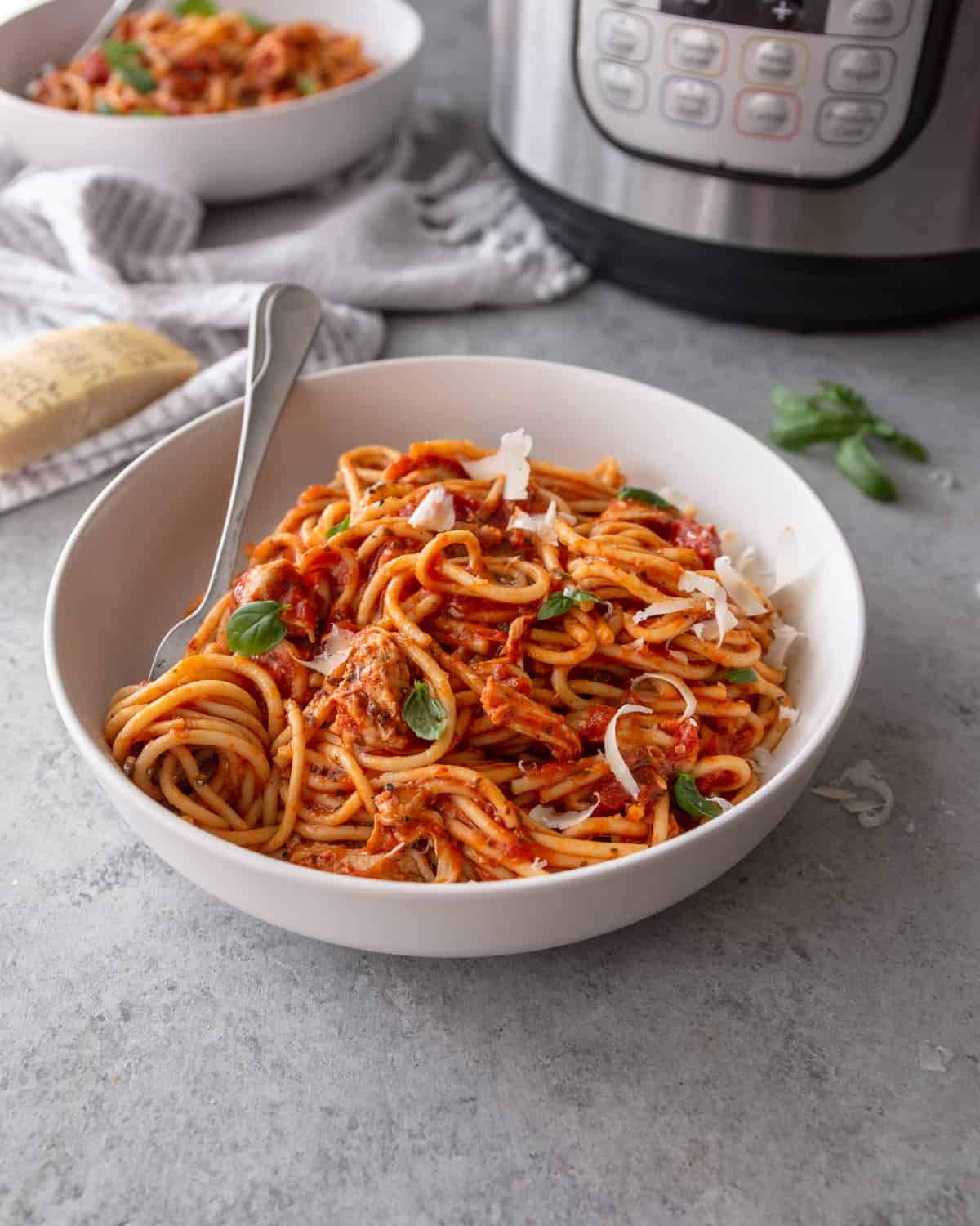 side image of Instant Pot chicken spaghetti in a white bowl with a silver fork