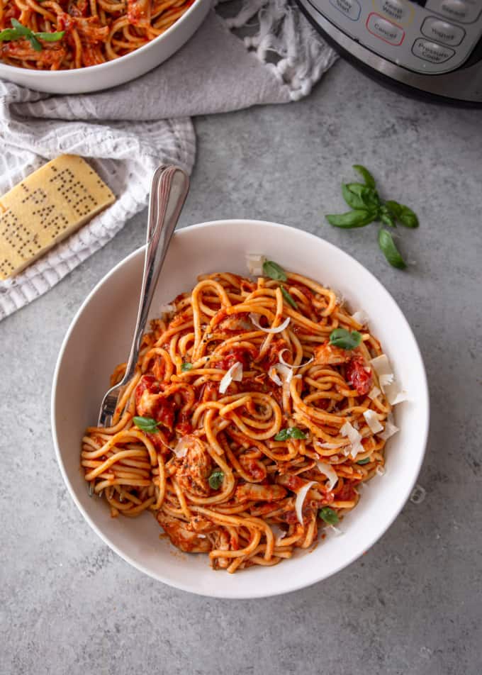 image of white bowl with chicken spaghetti and an instant pot in the background