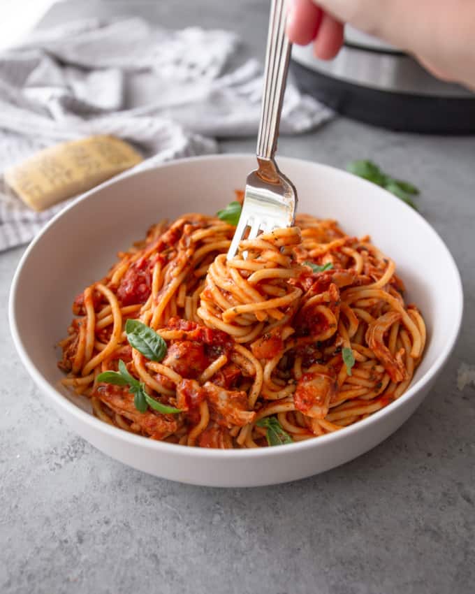 fork twirling instant pot spaghetti in a white bowl