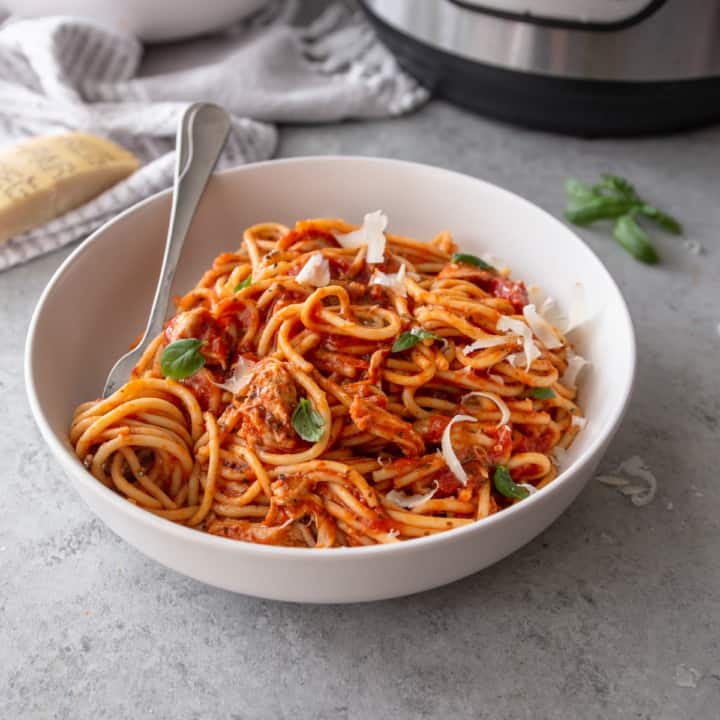 square image of instant pot chicken spaghetti in a white bowl with a silver fork