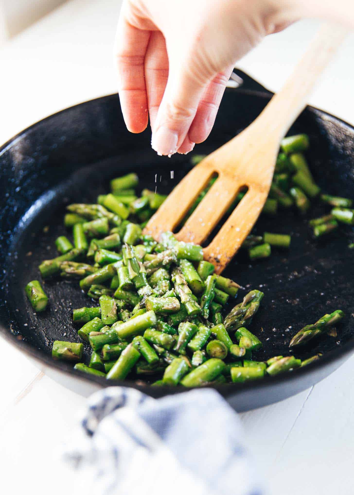 seasoning asparagus in a cast iron skillet