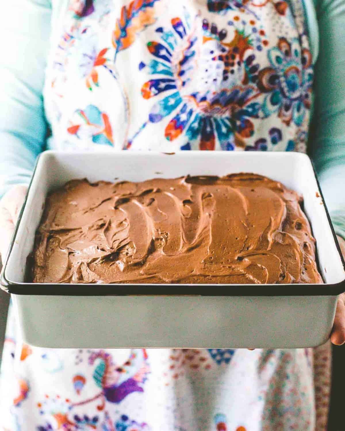 a chocolate cake with chocolate icing in a white baking pan