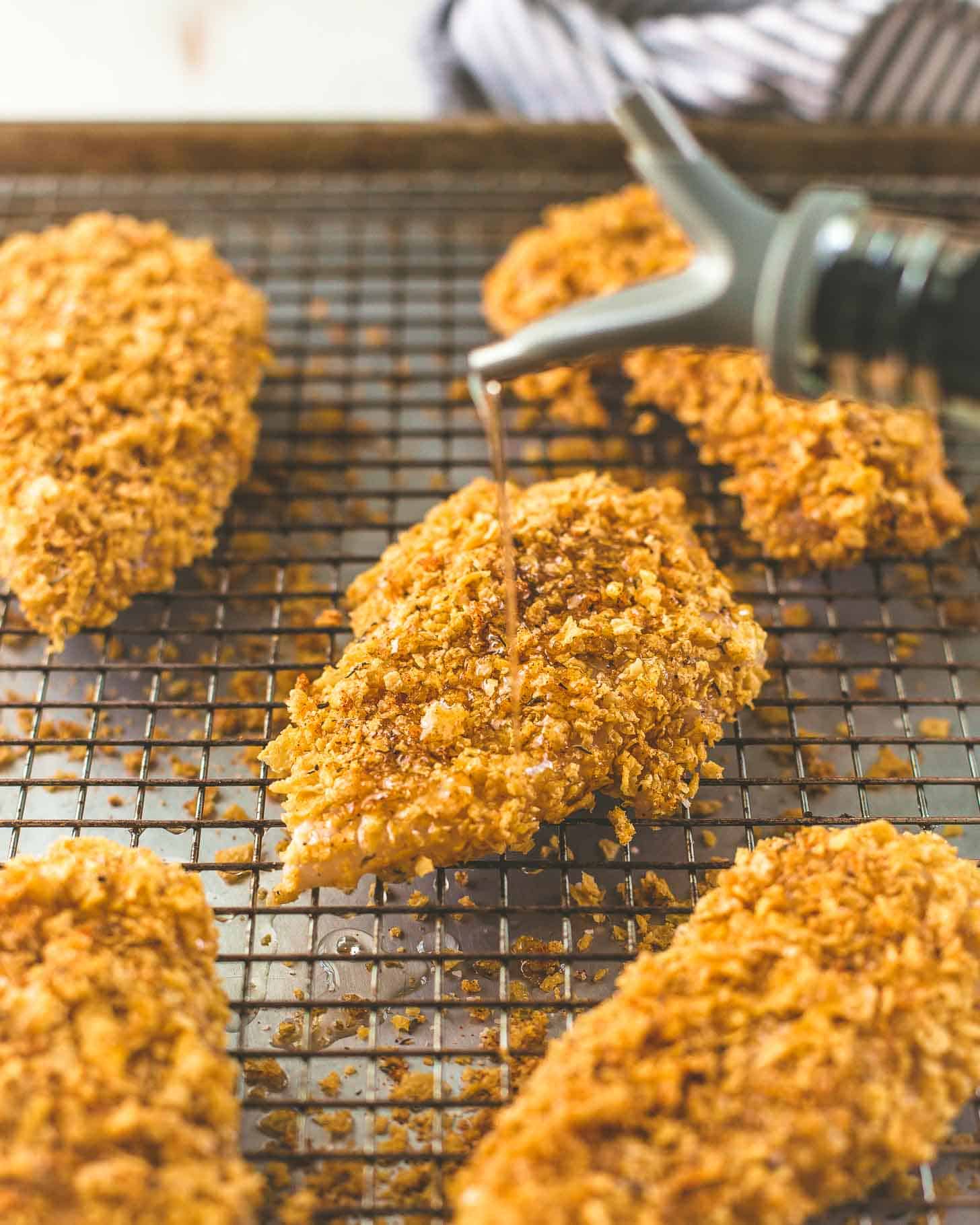 drizzling oil over baked chicken on a sheet pan