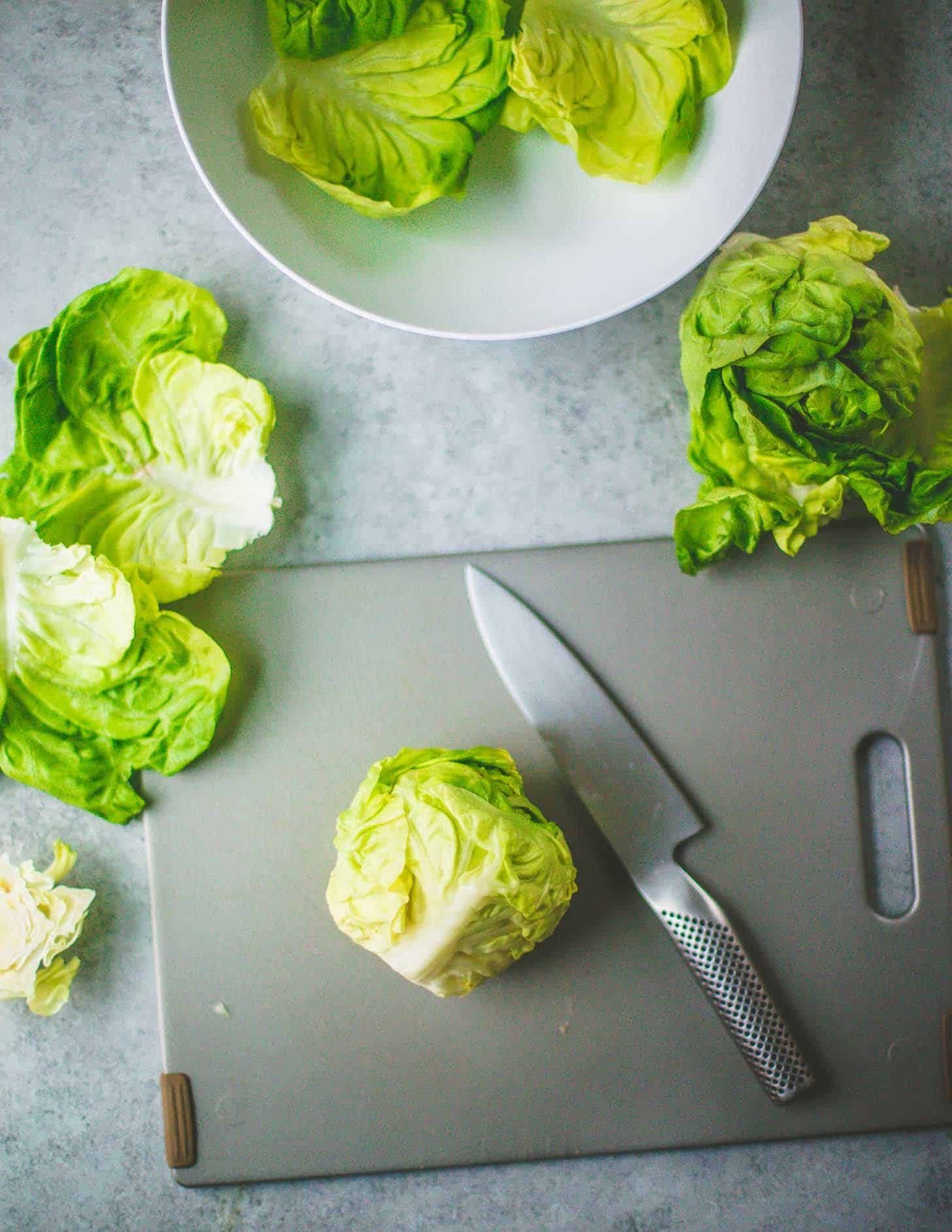 overhead image of a knife and Bibb lettuce on a grey countertop