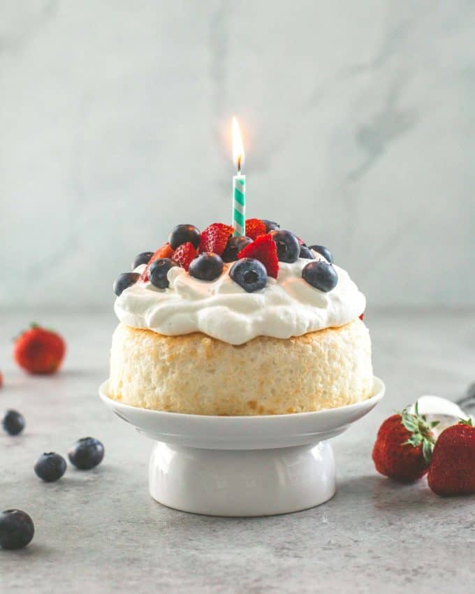 Smash Cake topped with berries and whipped cream with a lit candle