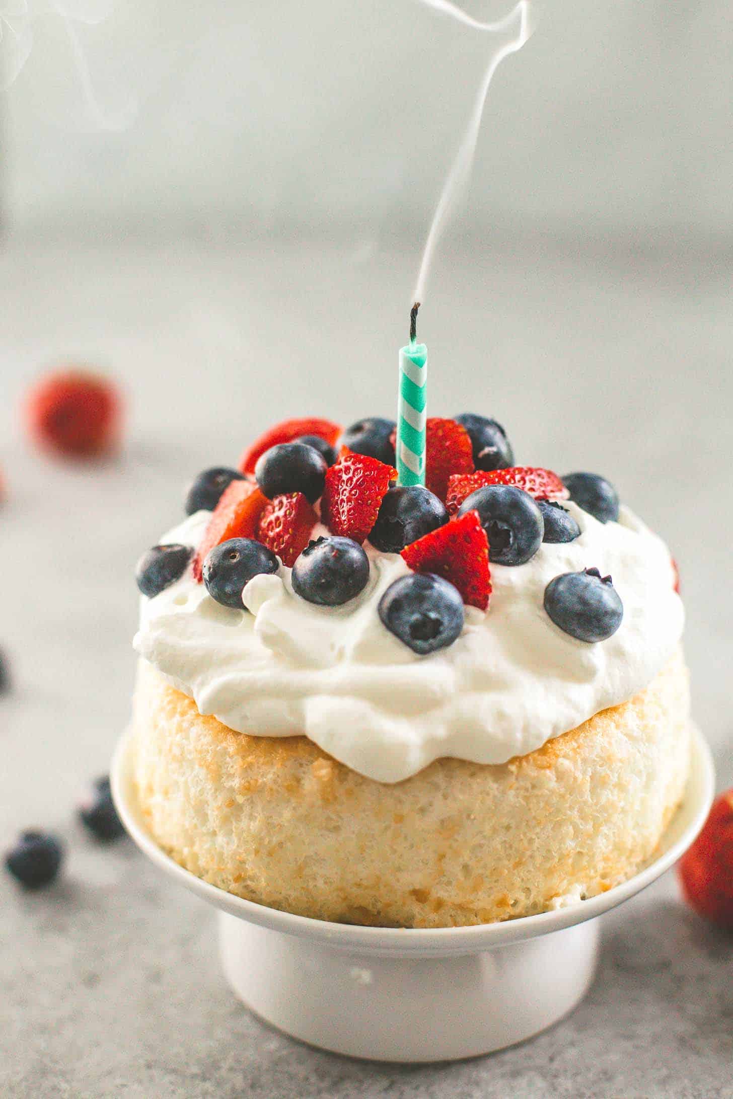 Smash Cake, topped with whipped cream and berries, with a candle