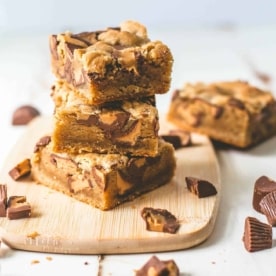 Peanut Butter Cup Cookie Bars stacked on a wooden board