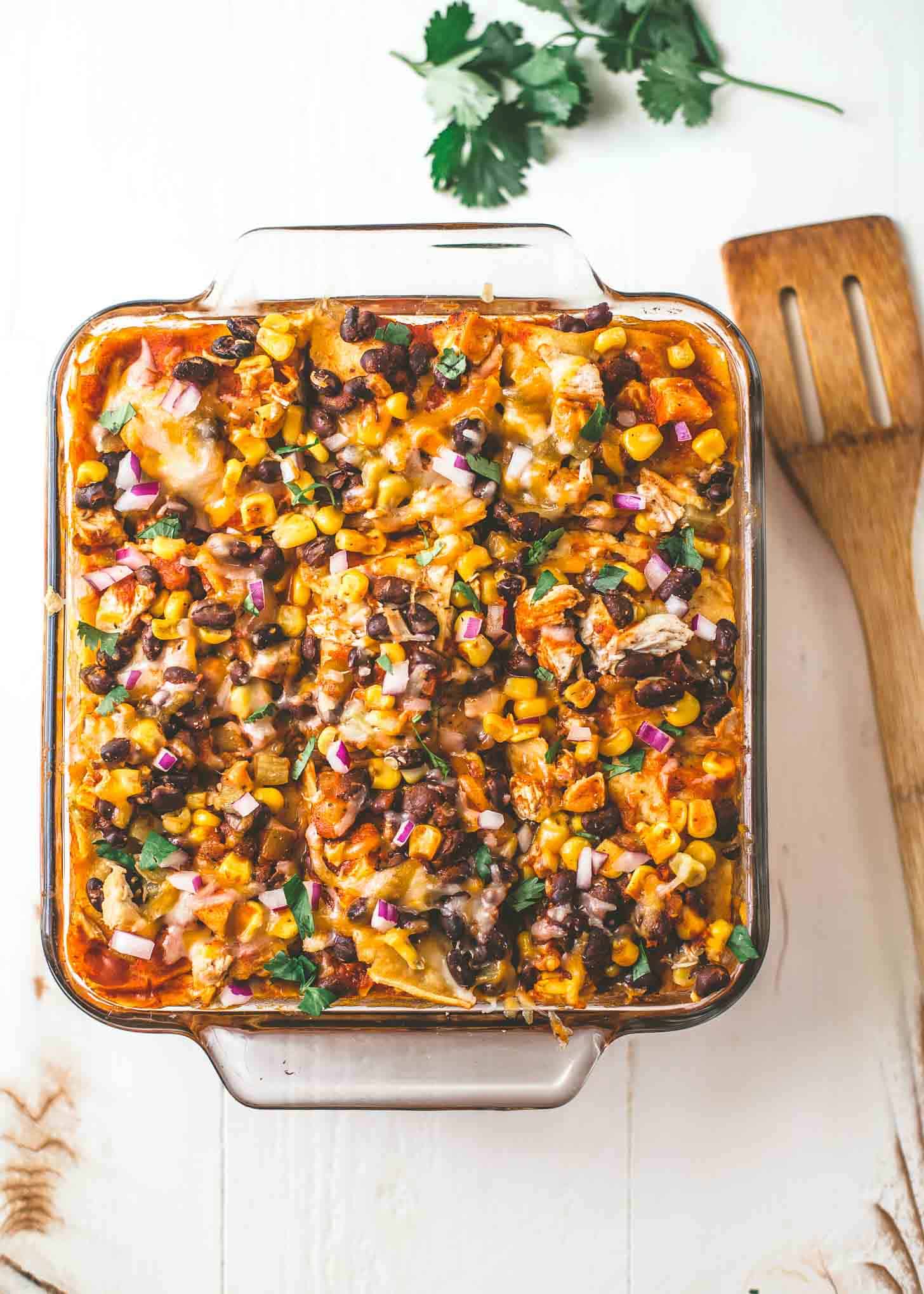 overhead image of Chicken Enchilada Casserole in a square baking dish on a white countertop