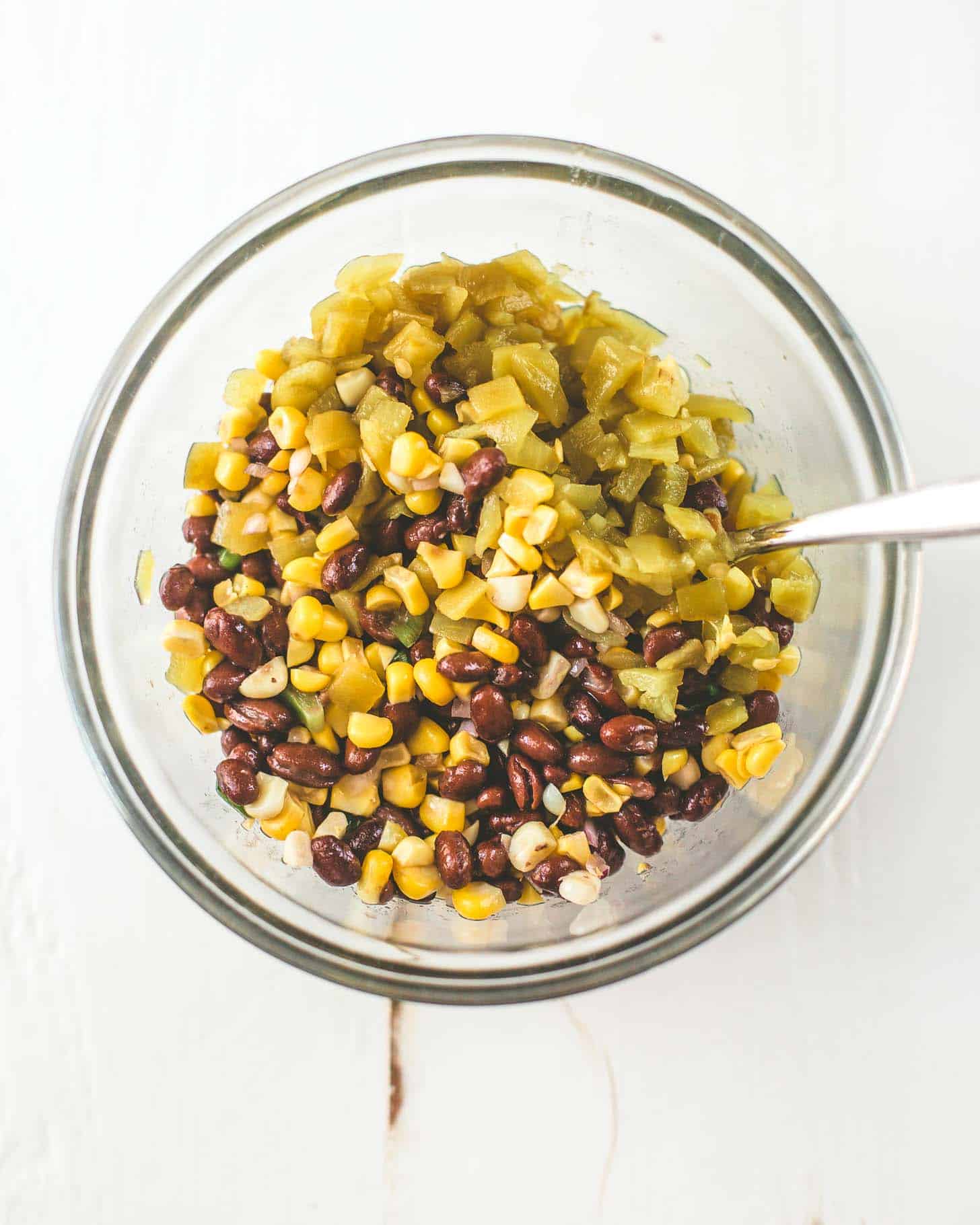 overhead image of green chilis, corn and black beans in a clear bowl