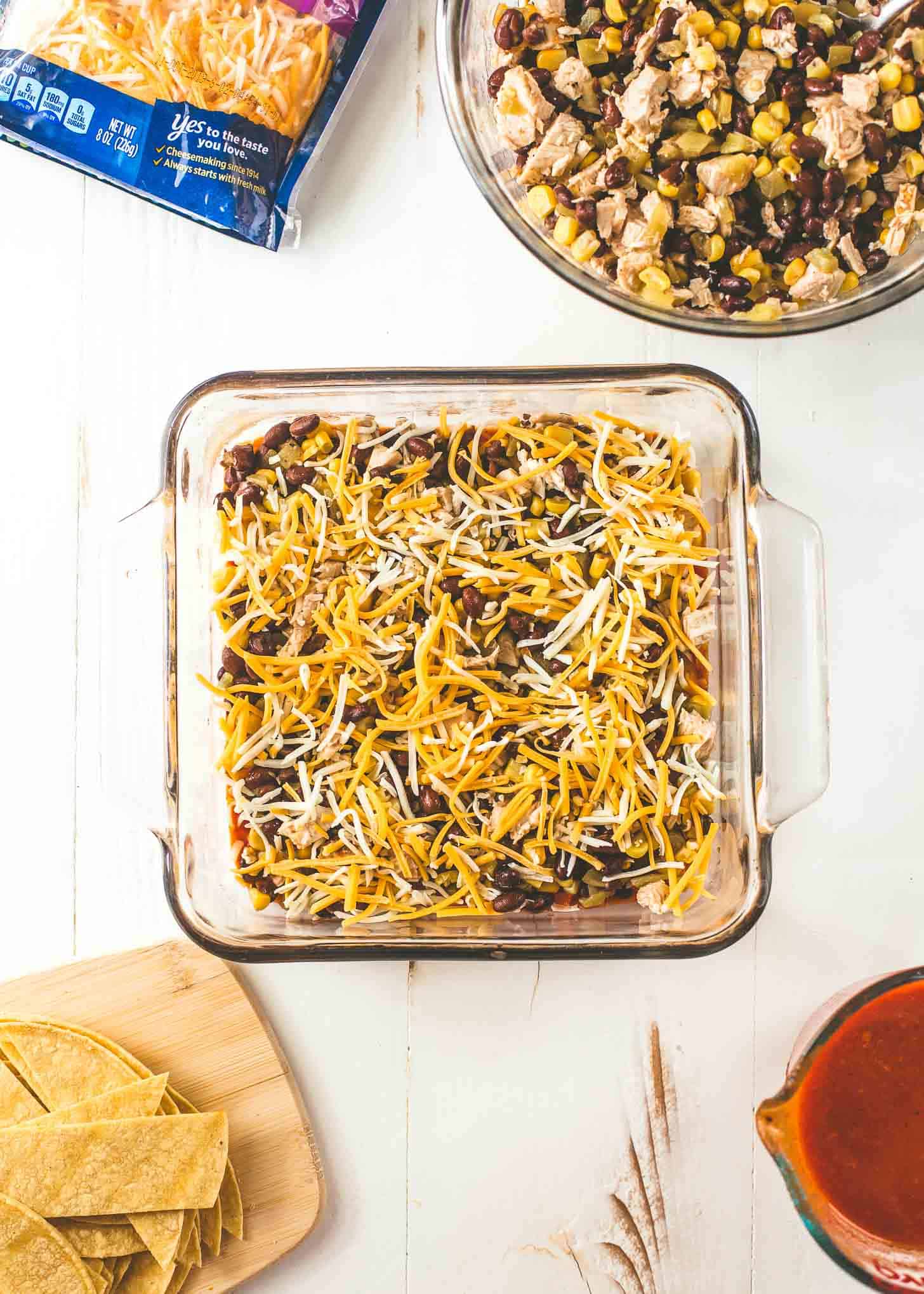 overhead image of unbaked Chicken Enchilada Casserole in a clear dish