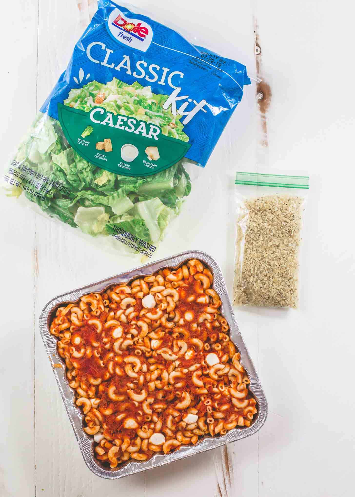 Chicken Parmesan Pasta Bake, salad and topping on a white table