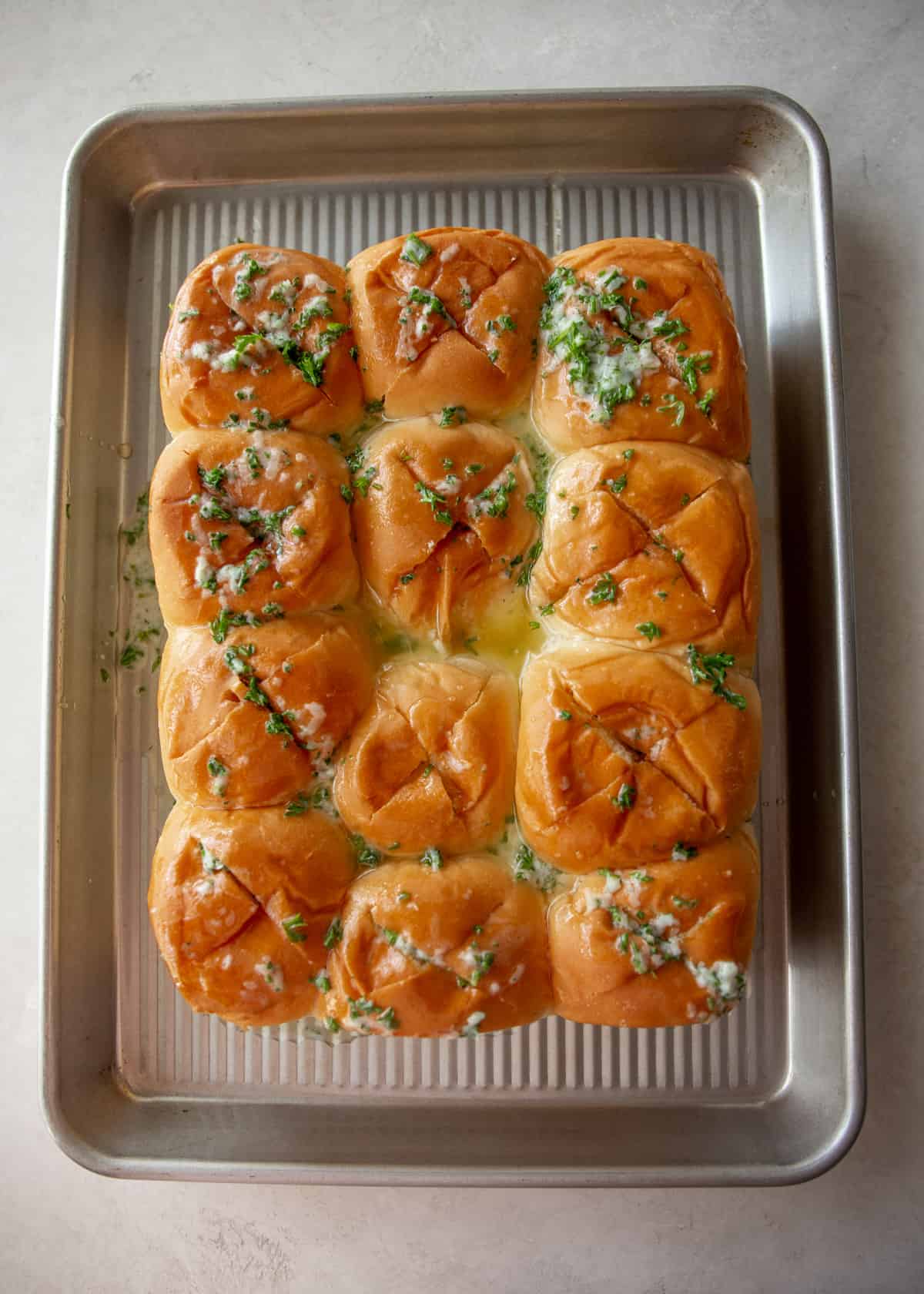 overhead image of hawaiian rolls drizzled with herb garlic butter