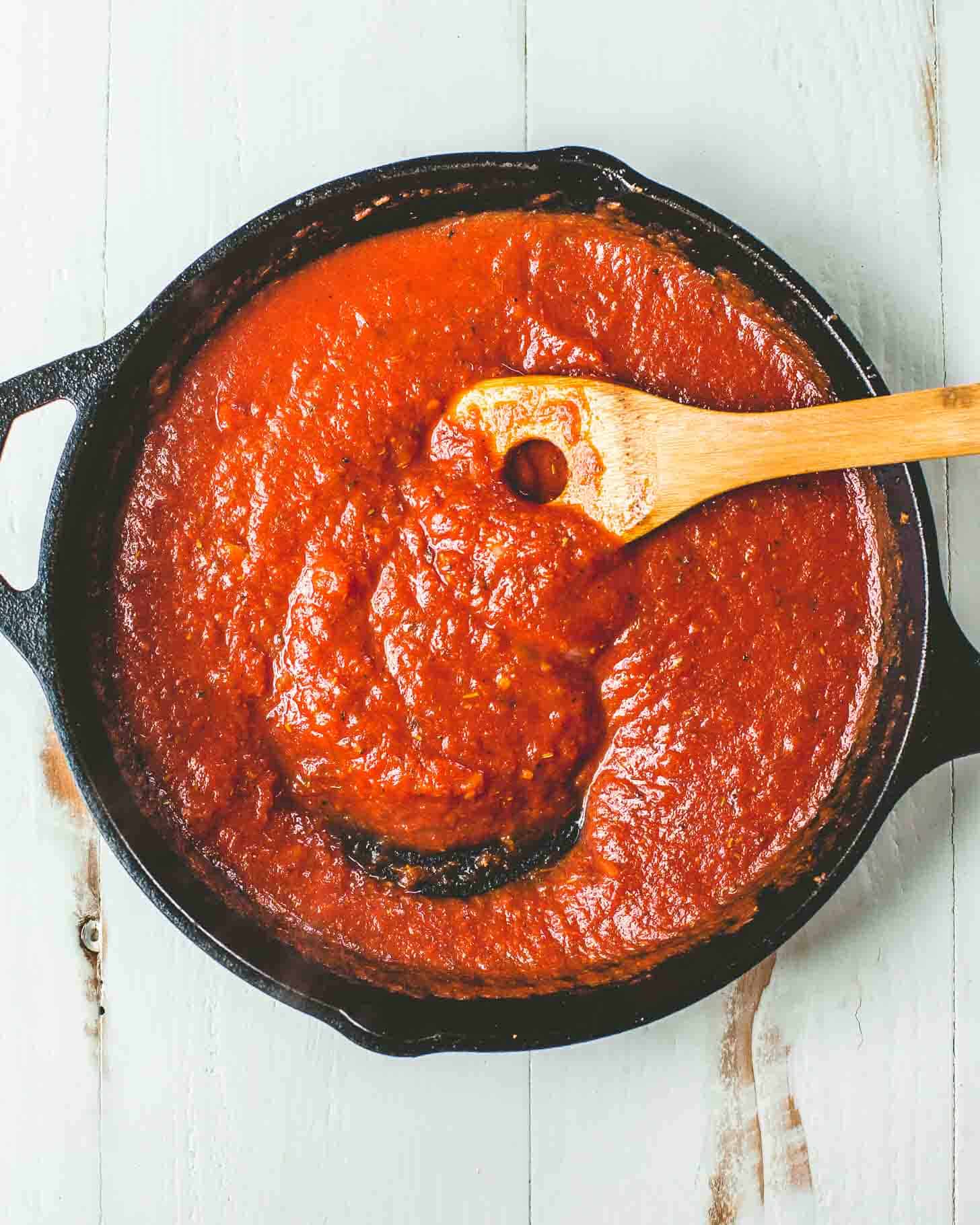 marinara sauce in a cast iron skillet with a wooden spoon