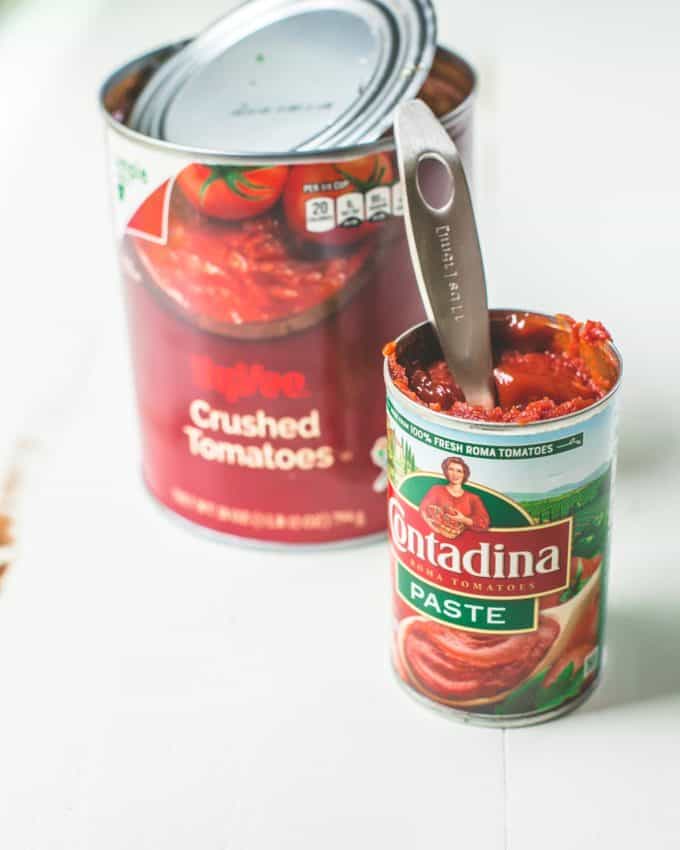 a can of tomato paste and a can of crushed tomatoes on a white countertop