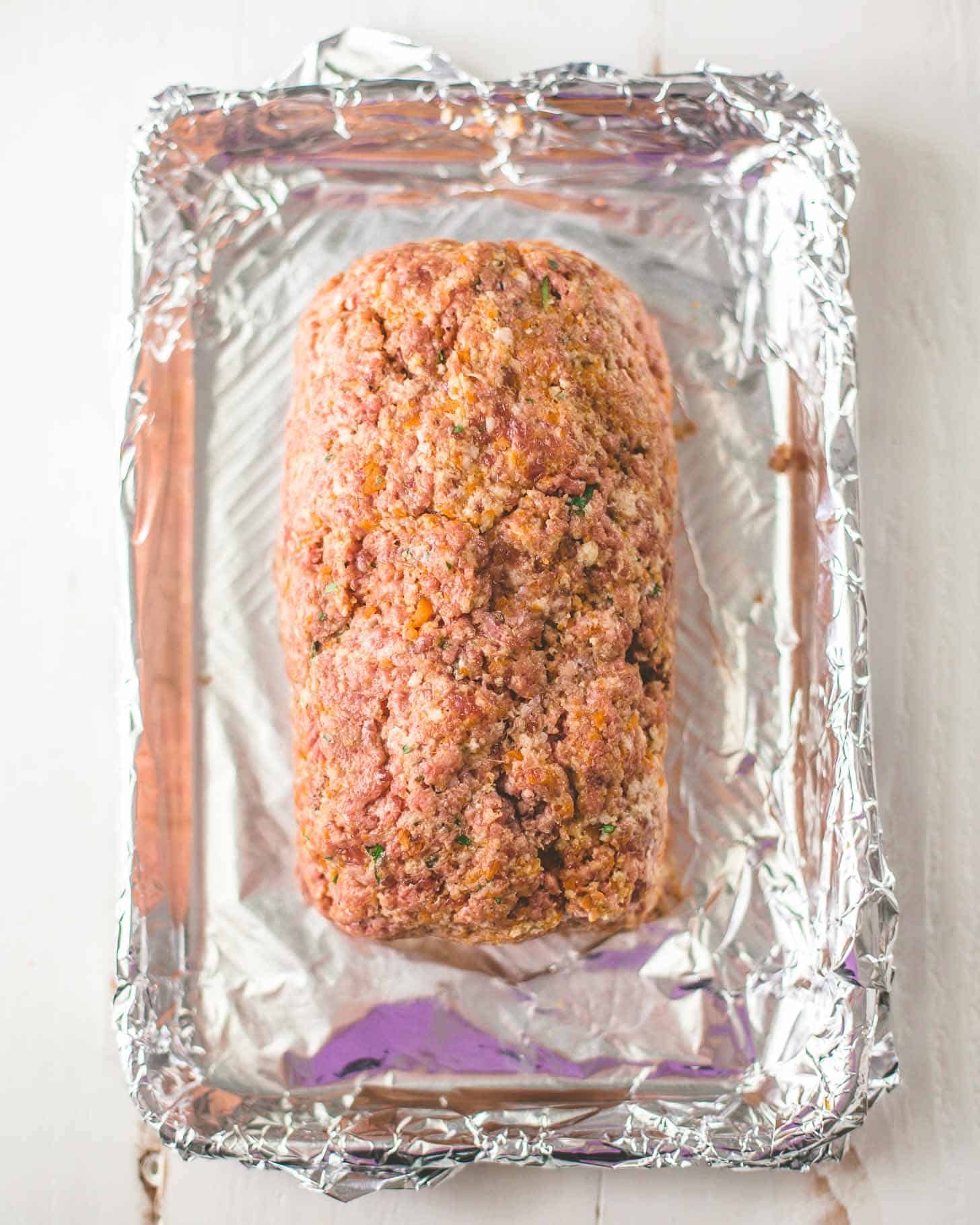 uncooked meatloaf on a foil lined sheet pan