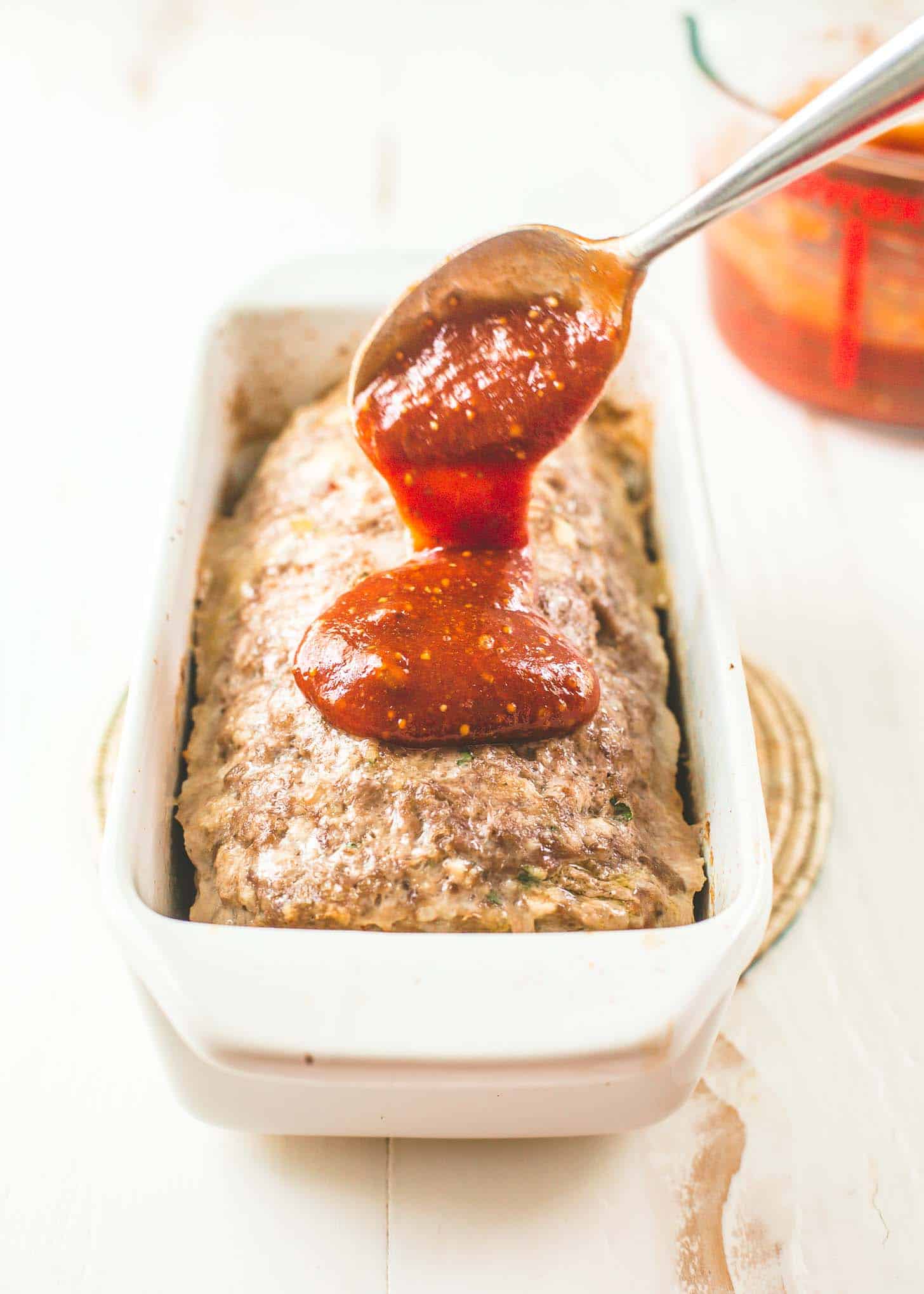 spooning glaze over uncooked meatloaf