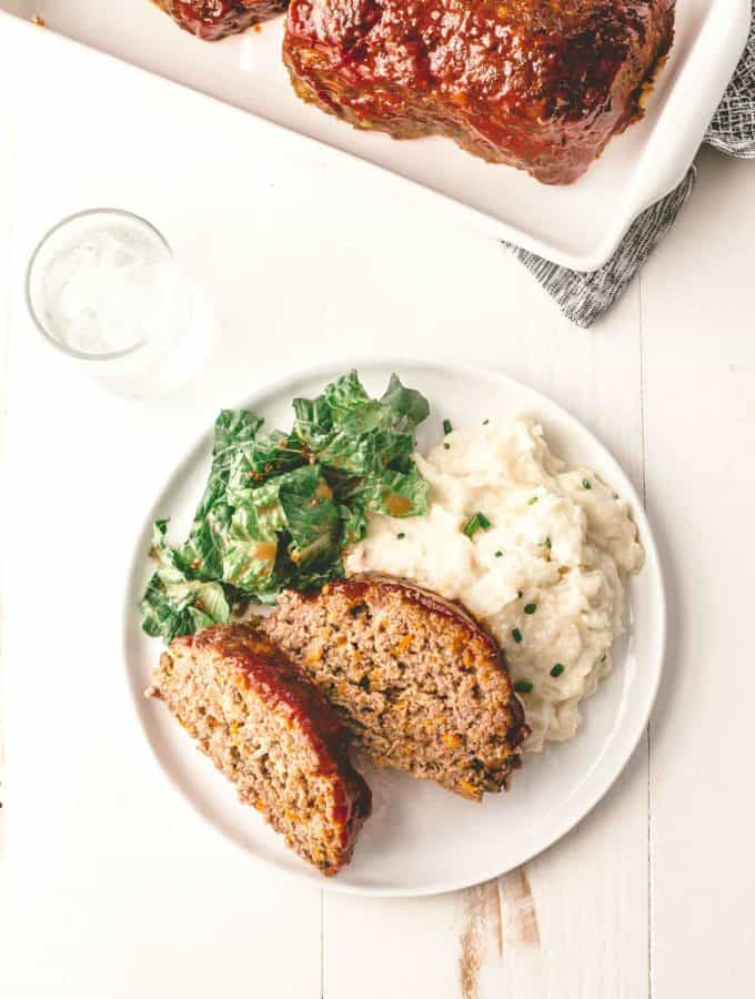 Classic Meatloaf, sliced on a white plate with mashed potatoes