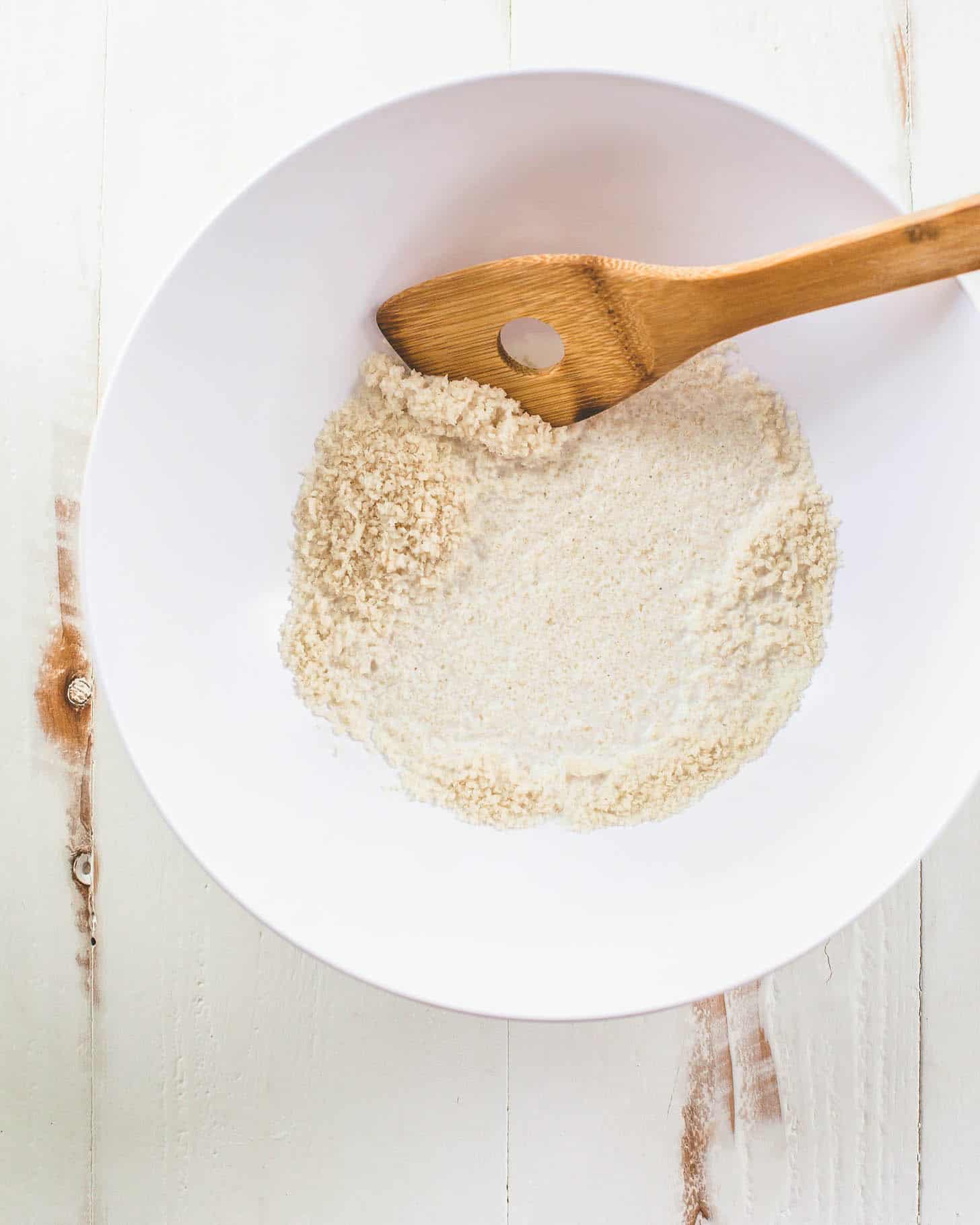 stirring bread crumbs in a white bowl