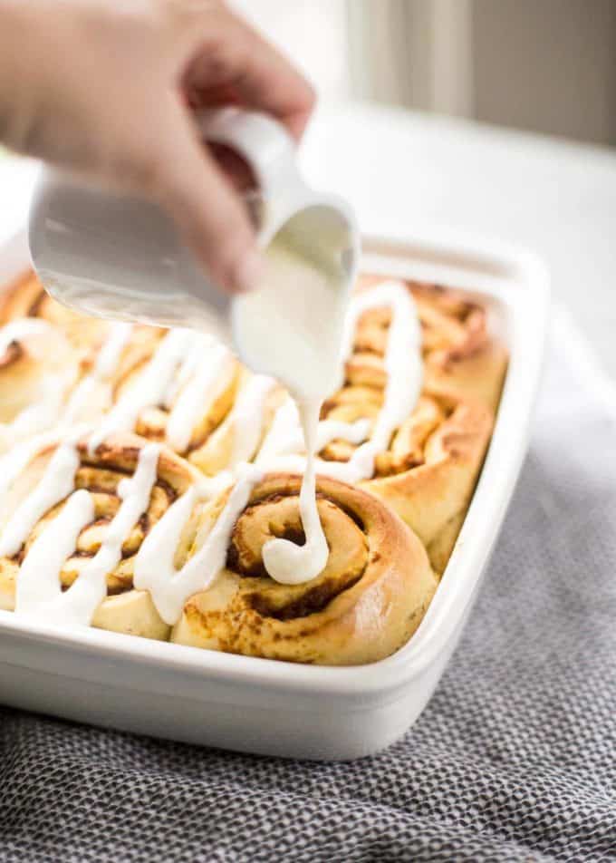 pouring icing on Pumpkin Cinnamon Rolls