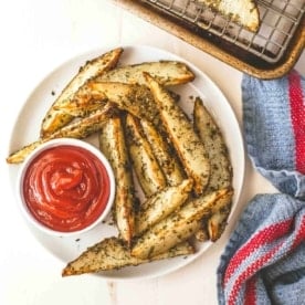 Oven Roasted Ranch Potato Wedges on a white plate with ketchup