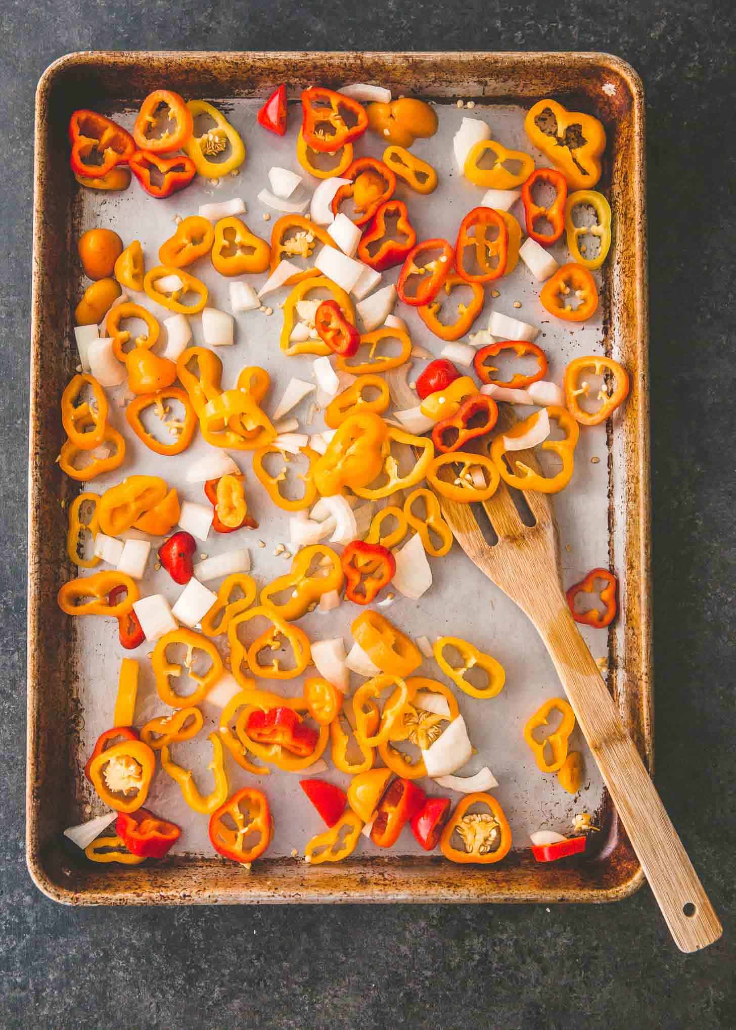 overhead image of sliced peppers and onions on a sheet pan