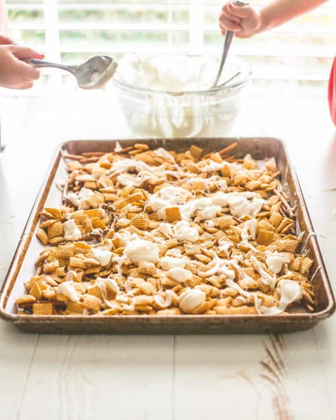 layering cereal and almond bark on pretzels