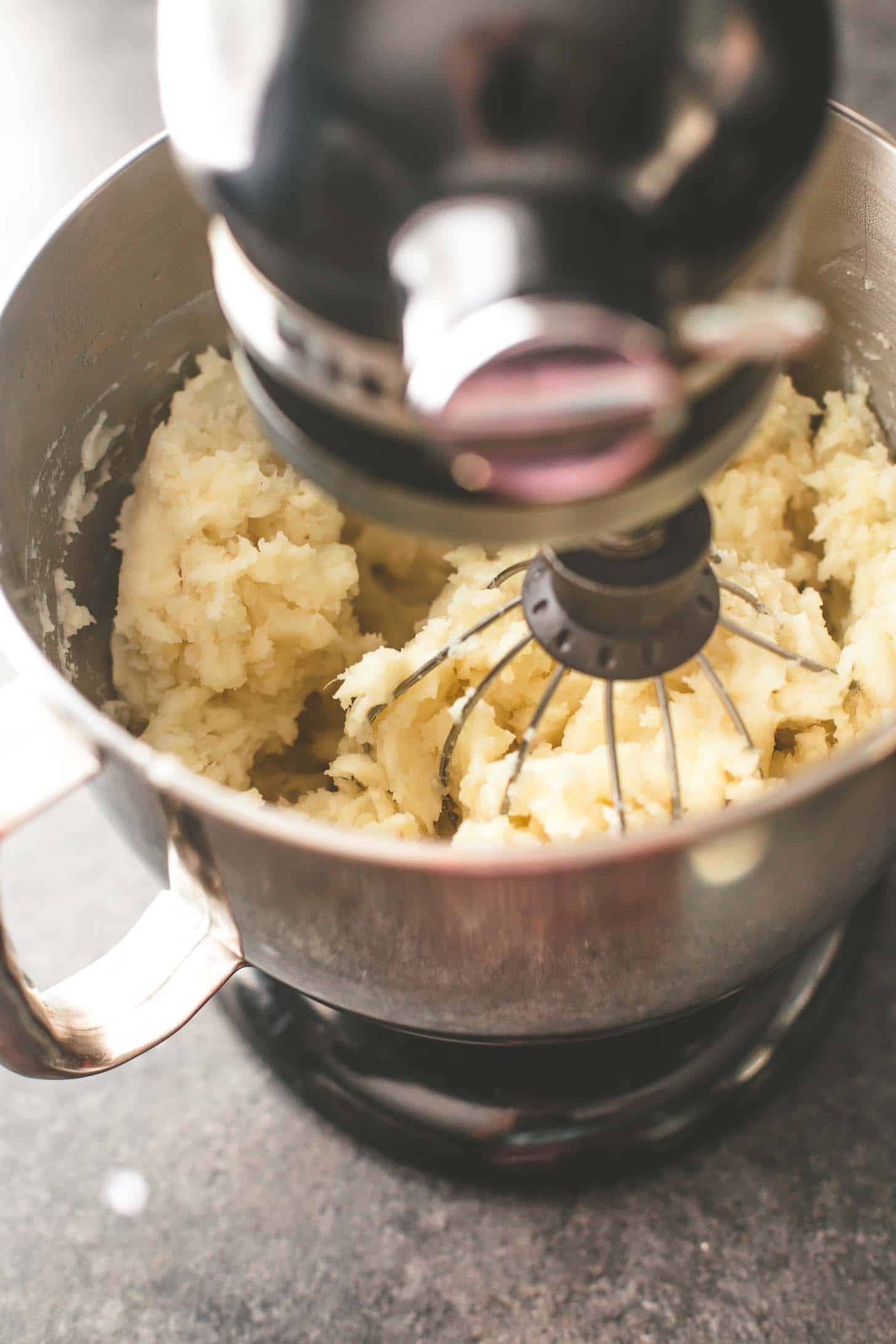 overhead image of mashing potatoes in a stand mixer