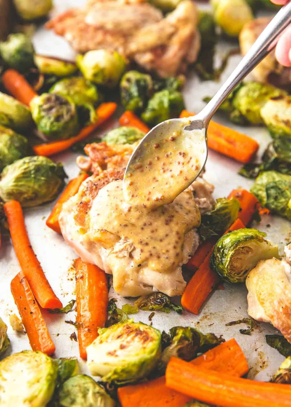 spooning dijon sauce on chicken