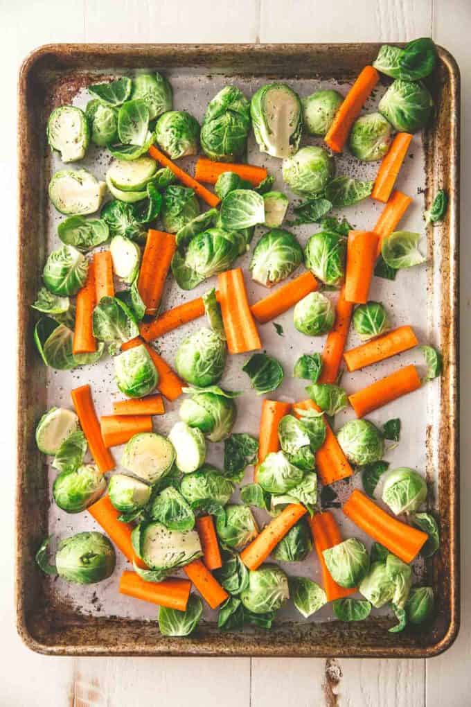 raw carrots and brussels sprouts on a sheet pan