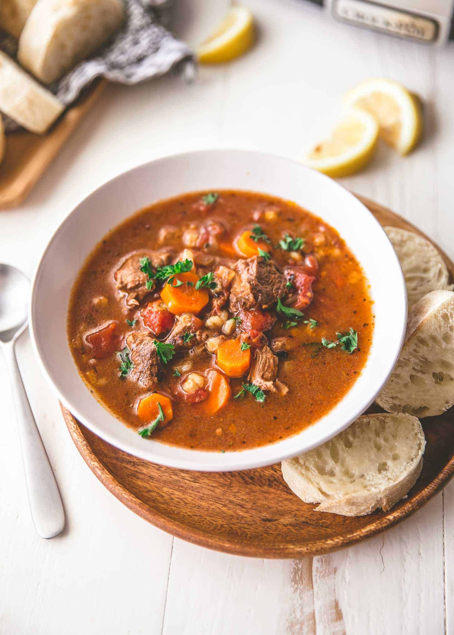 overhead image of Slow cooker beef and barley soup in a white bowl