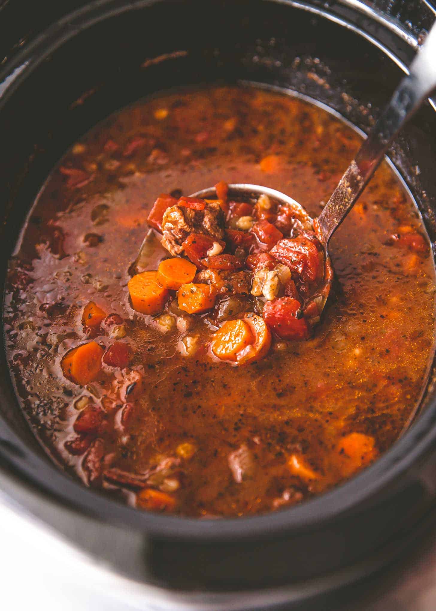 overhead image of beef and barley soup in the slow cooker