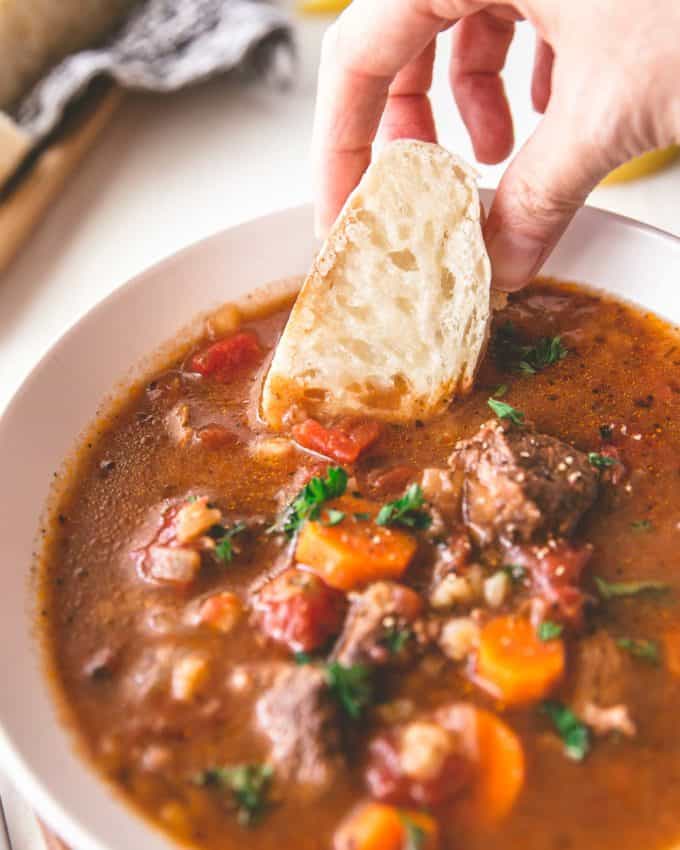 dipping bread into beef and barley soup