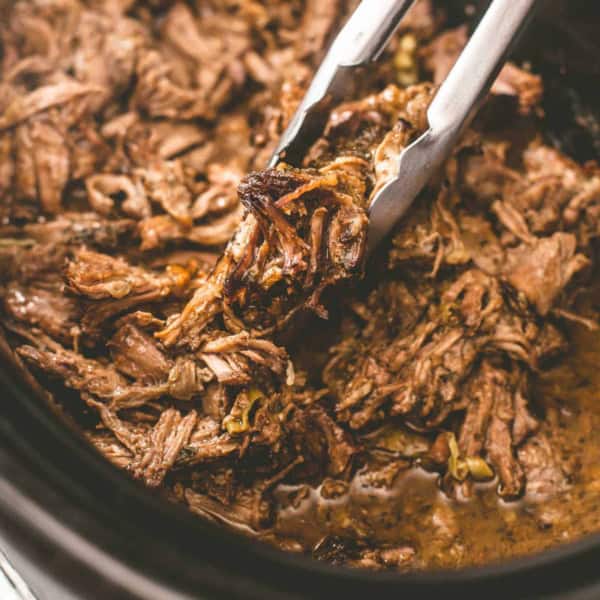 the bowl of a slow cooker with shredded pork mississippi roast
