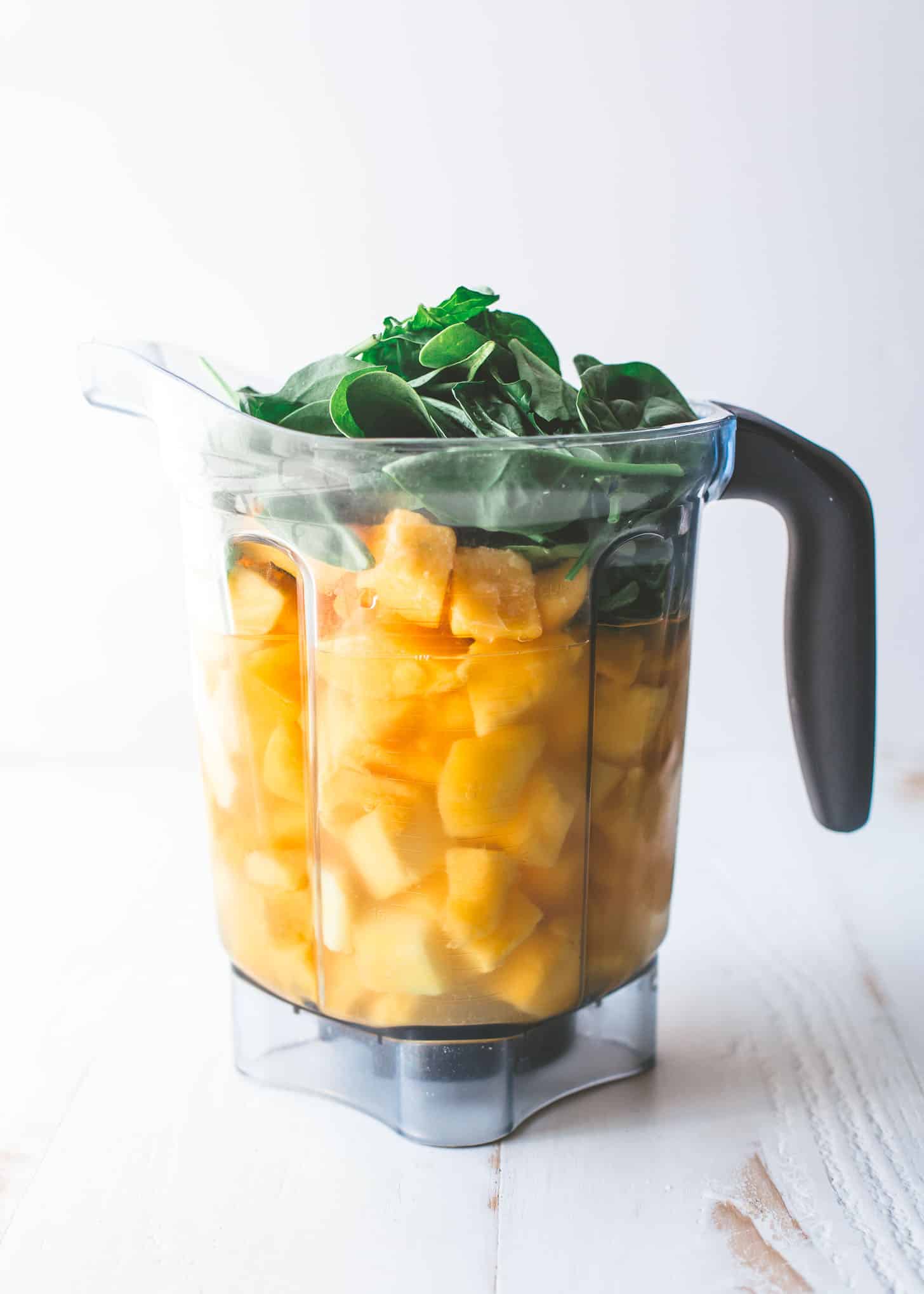 mango chunks and baby spinach in a blender