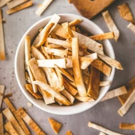 a small white bowl of tortilla strips on a sheet pan