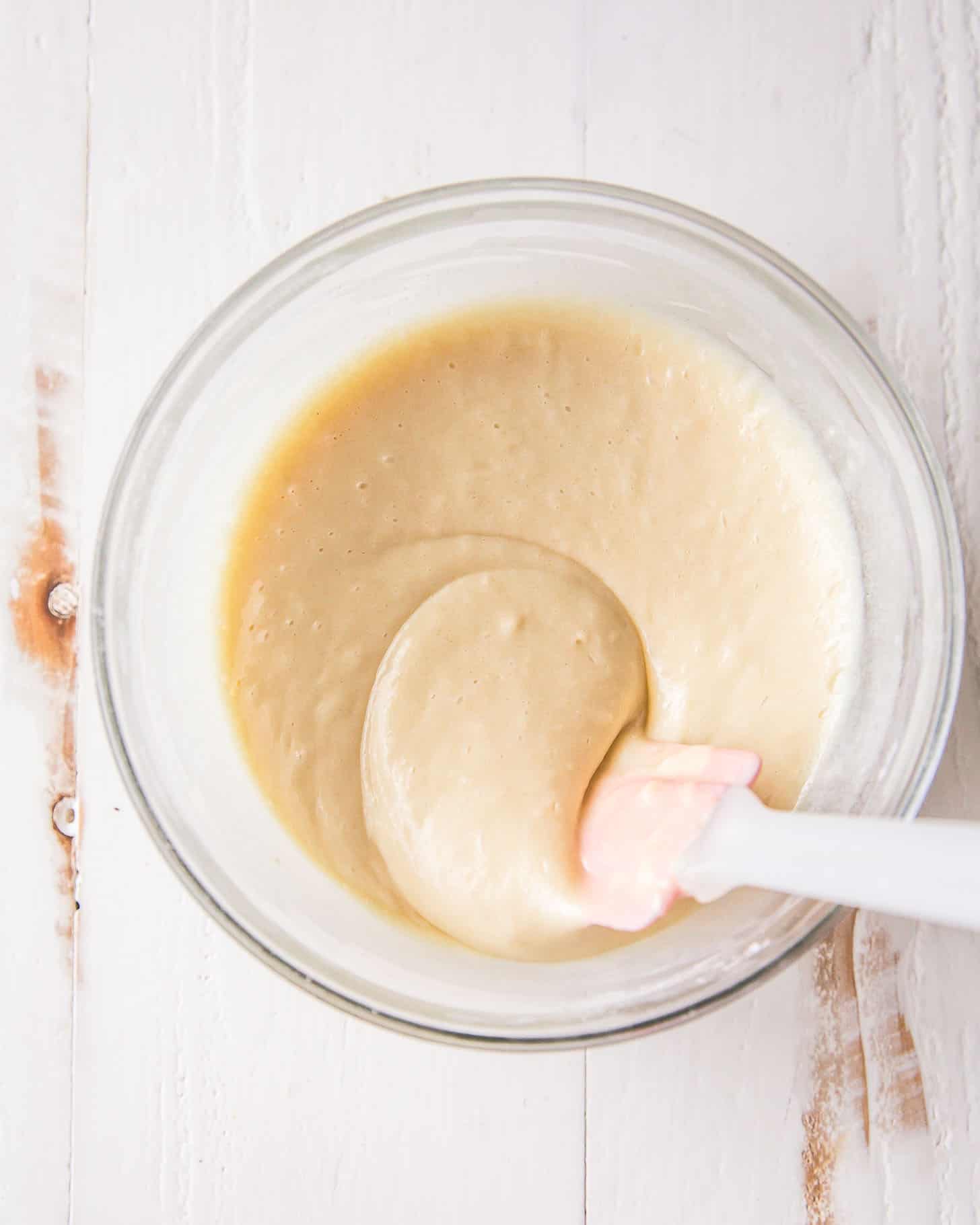 cake batter in a clear bowl with a spatula