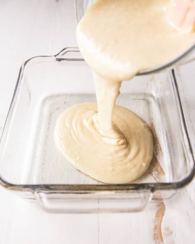pouring vanilla cake batter into a clear baking dish